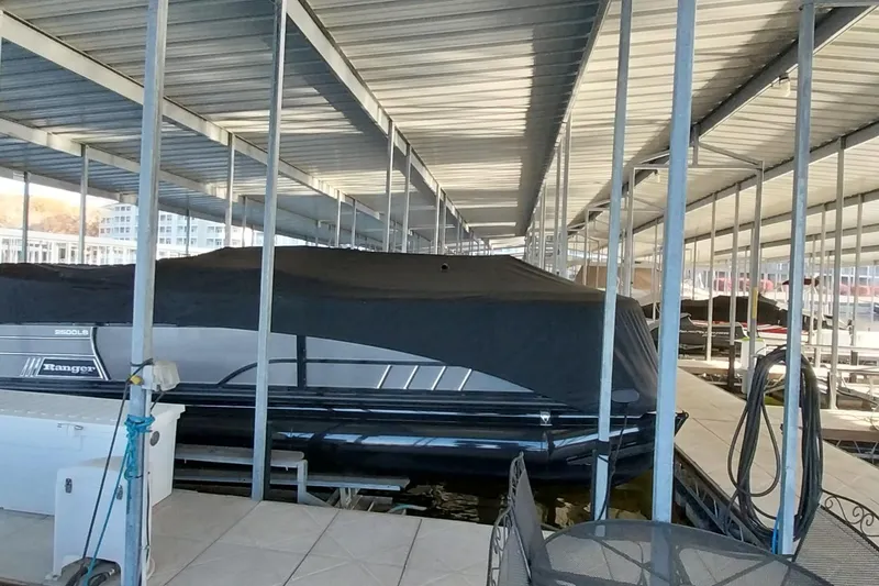 Slide: The Image of Covered 2023 Ranger 2500LS boat docked in a marina under a metal roof. - 45