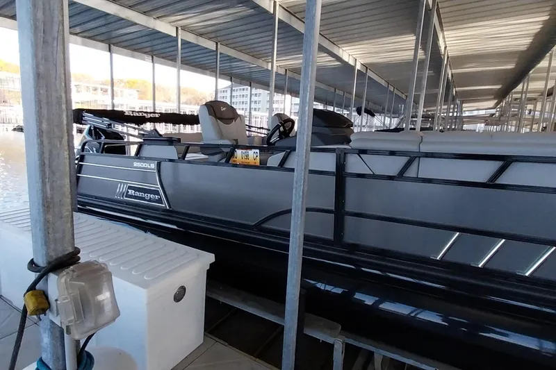 Slide: The Image of 2023 Ranger 2500LS pontoon boat docked under covered marina. - 49