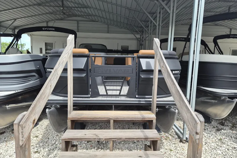 The Image of 2026 Sylvan L3 DLZ Bar pontoon boat under a metal canopy, viewed from the rear. - 1