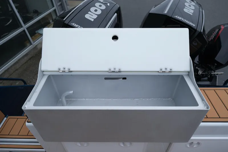 Slide: The Image of Open storage compartment on a 2026 Makaira 28 boat with Mercury engines in the background. - 24