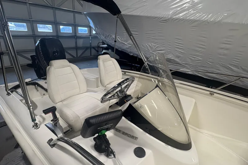 Slide: The Image of 2016 Boston Whaler 150 Super Sport boat interior with white seats and steering wheel. - 8