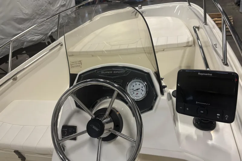 Slide: The Image of 2016 Boston Whaler 150 Super Sport boat dashboard with steering wheel and Raymarine display. - 9