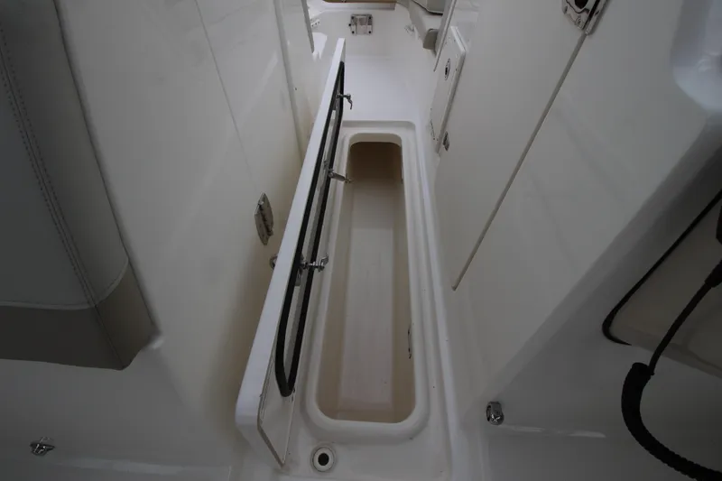 Slide: The Image of 2023 Boston Whaler 240 Vantage boat interior with seating, docked by waterfront. - 27