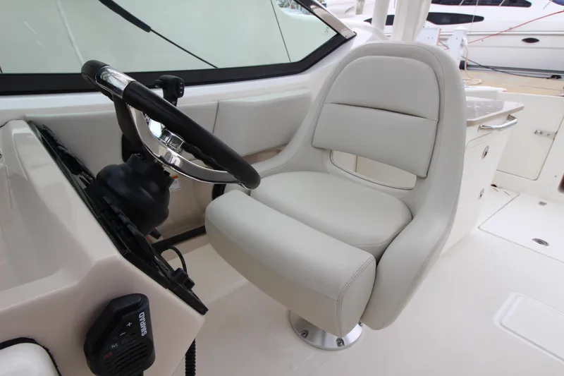 Slide: The Image of 2023 Boston Whaler 240 Vantage helm with navigation display, steering wheel, and throttle controls. - 31