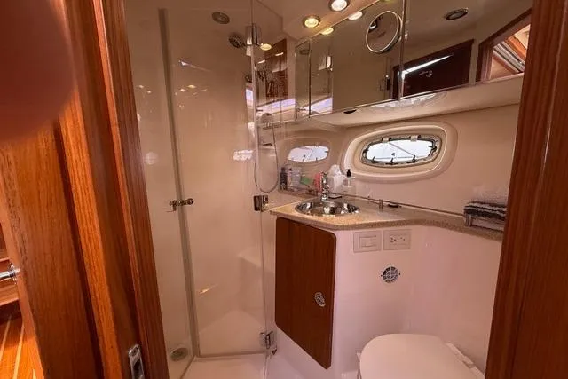 Slide: The Image of Bathroom interior of 2010 Tiara Yachts 3900 Open, featuring shower, sink, and porthole window. - 37