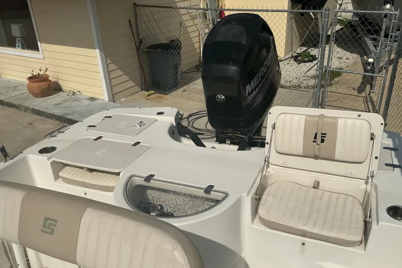 Slide: The Image of 2014 Carolina Skiff 198 DLV boat with Mercury outboard motor, beige seating, and storage compartments. - 9