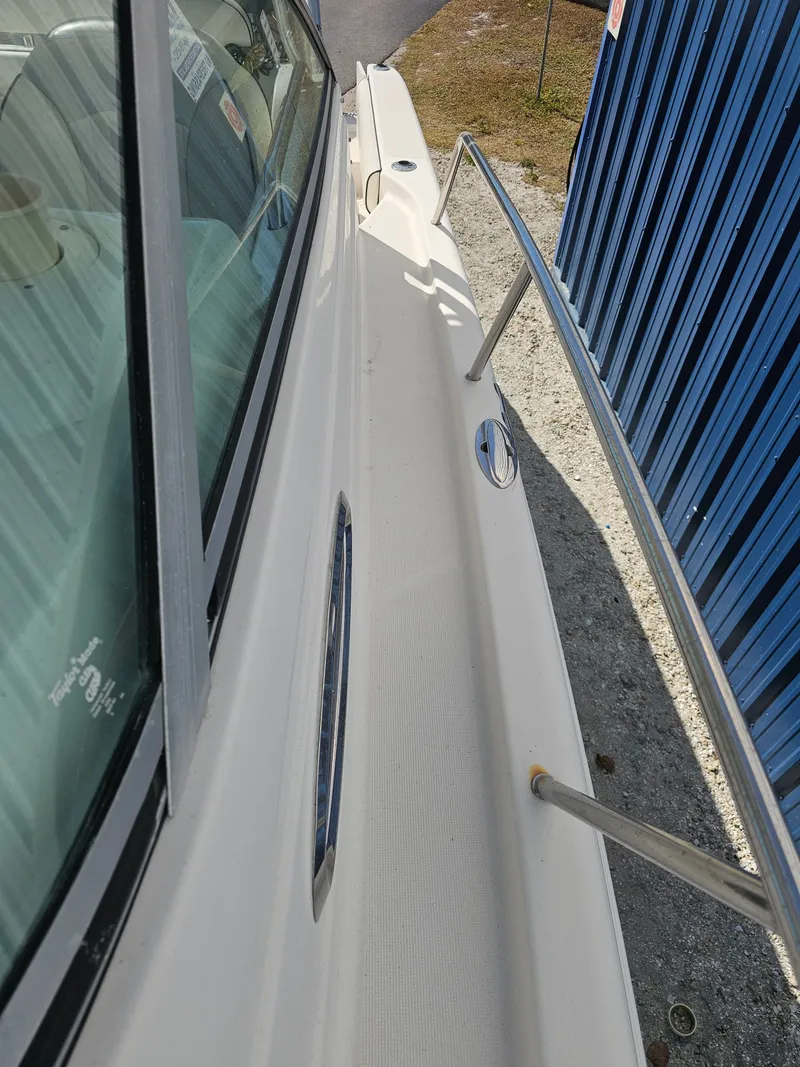 Slide: The Image of 2006 Robalo R265 Walkaround boat deck beside blue building. - 36