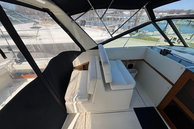 Slide: The Image of 1991 Tiara Yachts 3100 Open interior with white seating and marina view. - 19