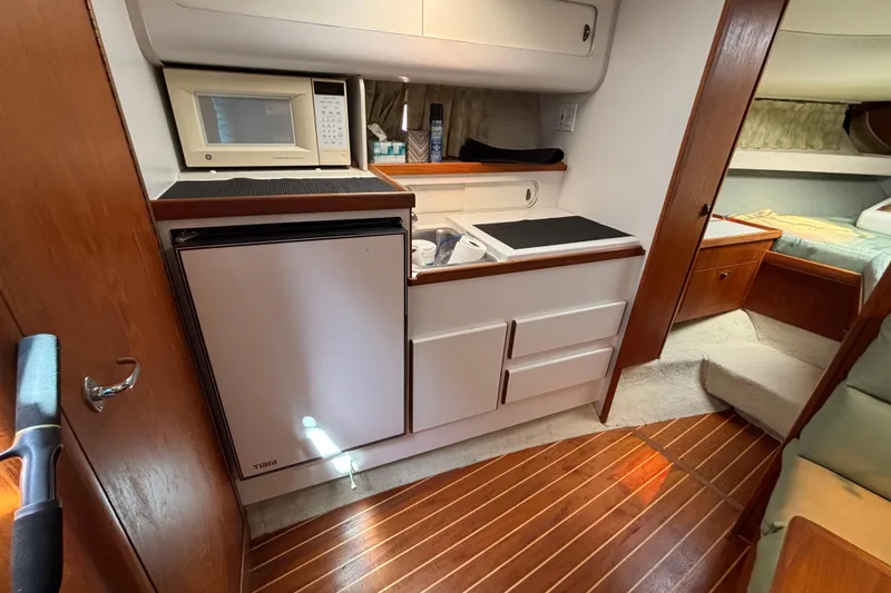 Slide: The Image of 1991 Tiara Yachts 3100 Open interior with kitchenette, microwave, and cozy cabin space. - 28