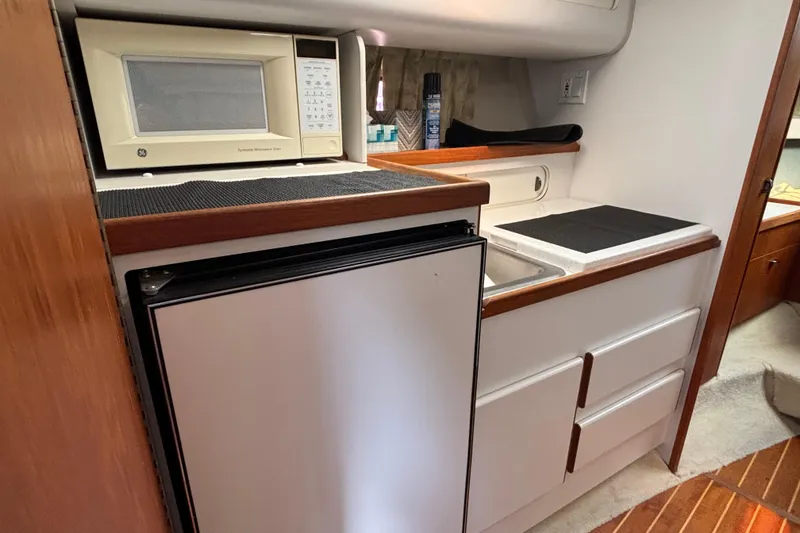 Slide: The Image of 1991 Tiara Yachts 3100 Open galley with microwave, fridge, and storage cabinets. - 30