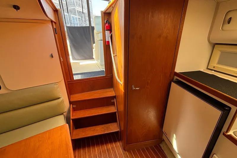 Slide: The Image of Interior of 1991 Tiara Yachts 3100 Open, featuring wooden stairs and compact kitchenette. - 32