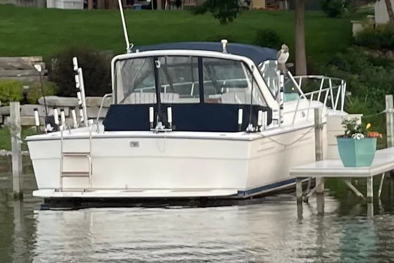 Slide: The Image of 1991 Tiara Yachts 3100 Open docked by a lakeside with greenery. - 6
