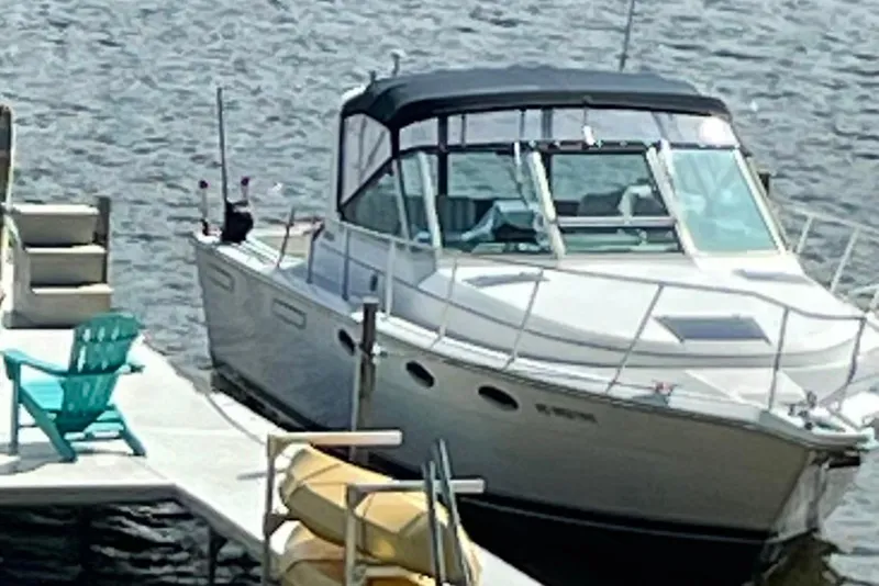 Slide: The Image of 1991 Tiara Yachts 3100 Open docked by the water with turquoise chair nearby. - 7