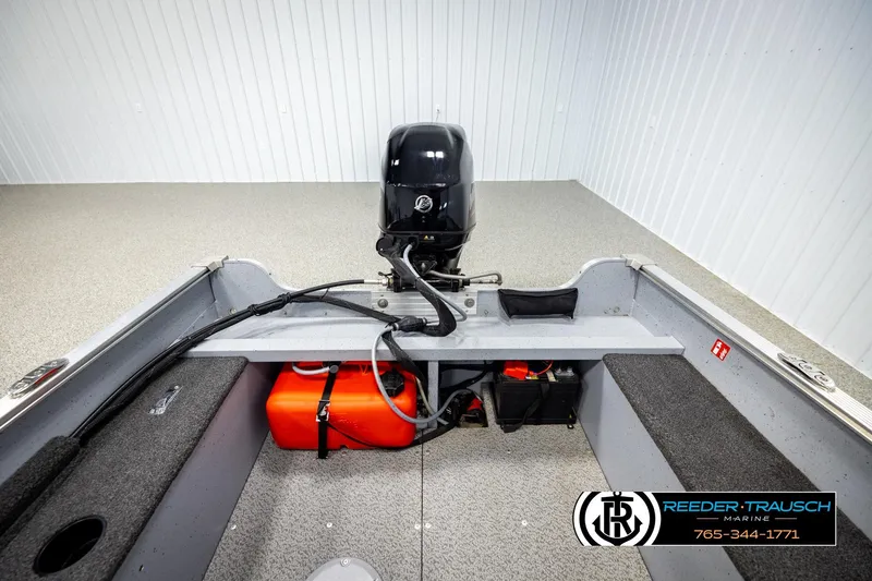 Slide: The Image of 2025 Lund 1600 Fury SS boat interior with motor and fuel tank, displayed in showroom. - 16