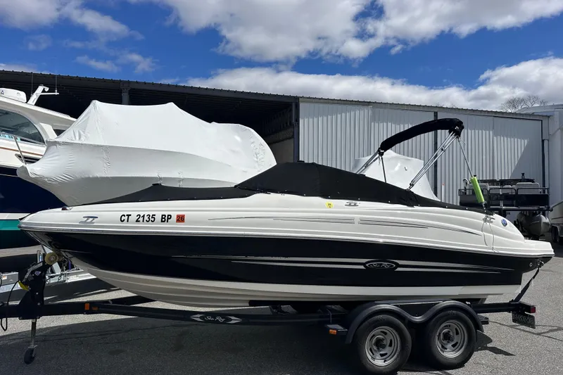 The Image of 2012 Sea Ray 200 Sundeck boat on trailer, covered and parked outdoors. - 0