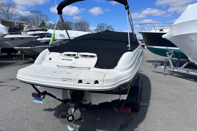 Slide: The Image of 2012 Sea Ray 200 Sundeck boat with black cover, parked on a trailer. - 2