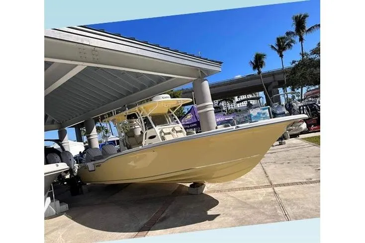 Slide: The Image of 2026 Key West 291 FS boat displayed outdoors under a canopy with palm trees nearby. - 9