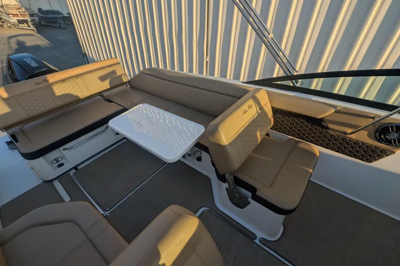 Slide: The Image of 2022 Sea Ray SDX 250 Outboard boat interior with beige seating and a white table. - 12