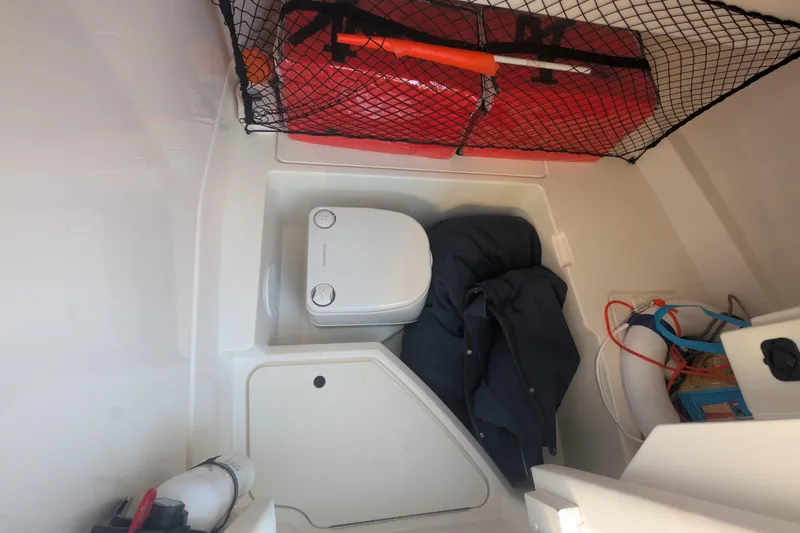 Slide: The Image of Interior storage of 2022 Sea Ray SDX 250 Outboard with portable toilet and safety gear. - 23