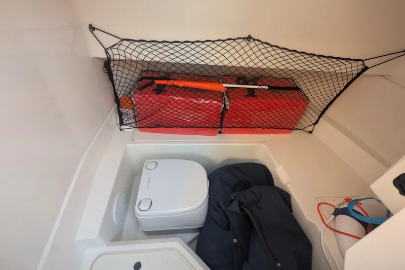 Slide: The Image of Interior storage of 2022 Sea Ray SDX 250 Outboard with portable toilet and safety gear. - 24