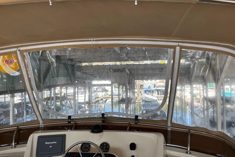 Slide: The Image of 2007 Mainship 34 Trawler helm view, docked in a marina with clear canopy enclosure. - 12