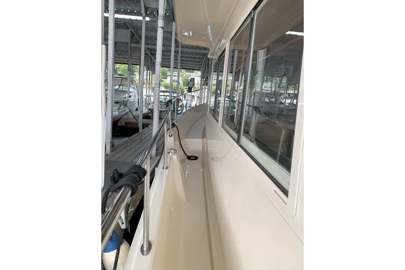 Slide: The Image of 2007 Mainship 34 Trawler side deck view in marina, showcasing sleek design and railing. - 4