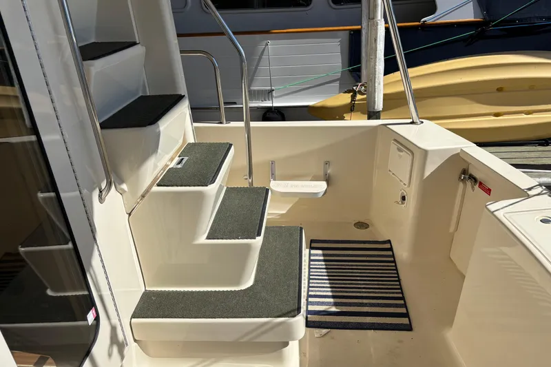 Slide: The Image of 2007 Mainship 34 Trawler cockpit with steps, striped mat, and docked boat view. - 6