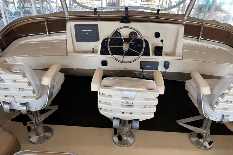 Slide: The Image of 2007 Mainship 34 Trawler helm with three white captain chairs and navigation equipment. - 8