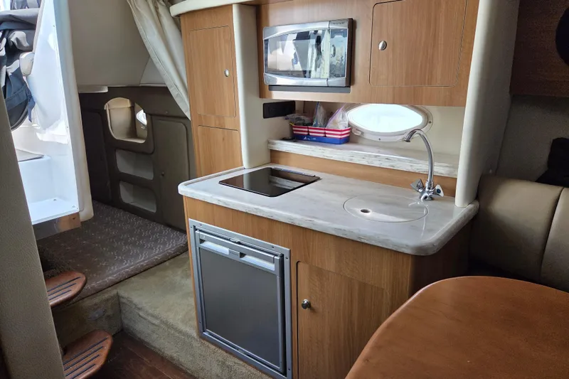 Slide: The Image of 2014 Rinker 290 Express Cruiser interior with kitchenette, microwave, and sink. - 22