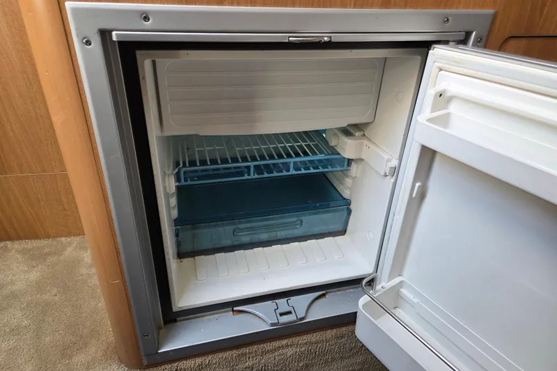 Slide: The Image of Open refrigerator inside 2014 Rinker 290 Express Cruiser, showcasing interior storage space. - 24