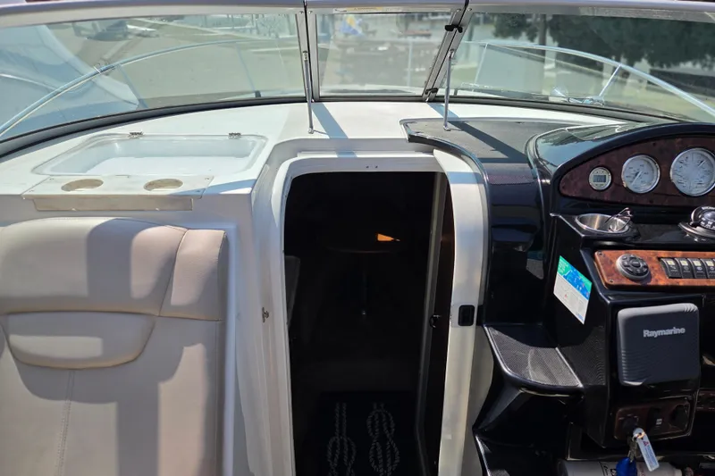 Slide: The Image of 2014 Rinker 290 Express Cruiser cockpit with steering controls and cabin entrance. - 31