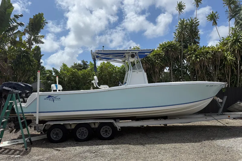 The Image of 2006 Ocean Runner 2900 C/C Open Fisherman boat on trailer, surrounded by tropical trees. - 1
