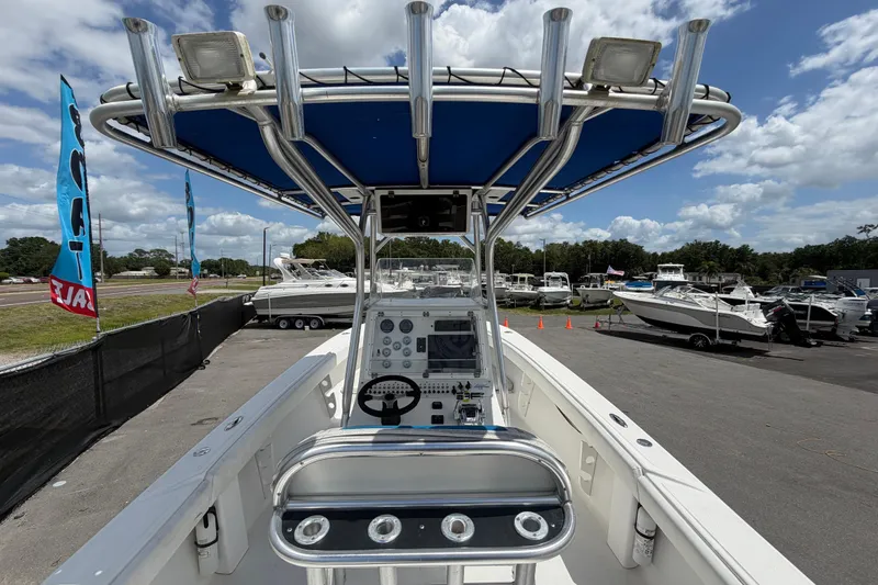 Slide: The Image of 2006 Ocean Runner 2900 C/C Open Fisherman boat with blue canopy, docked under cloudy sky. - 28