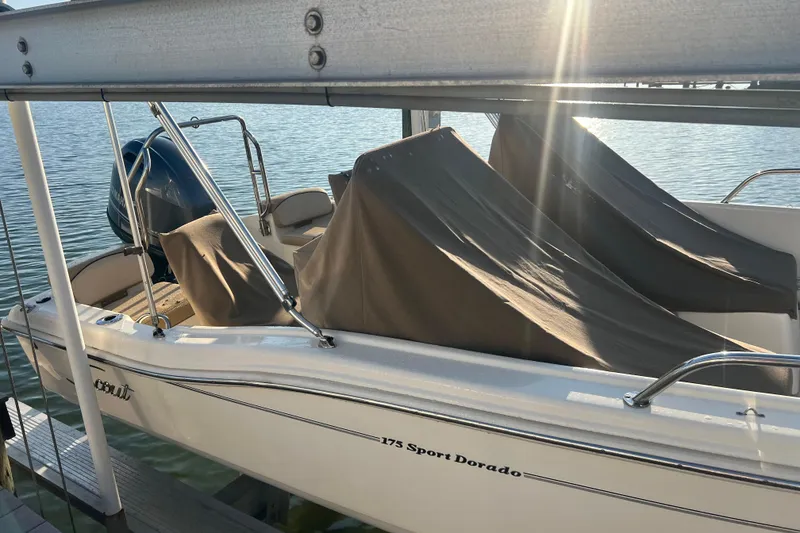 Slide: The Image of 2018 Scout 175 Sport Dorado boat docked with protective covers, sunlight reflecting on water. - 3