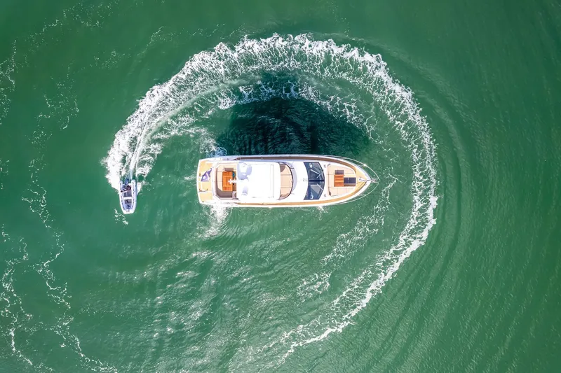 Slide: The Image of Aerial view of 2018 Sunseeker Manhattan 52 yacht making a circular wake in green water. - 14