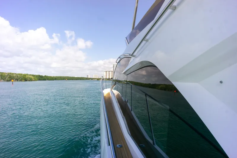 Slide: The Image of 2018 Sunseeker Manhattan 52 yacht cruising on a serene waterway under a partly cloudy sky. - 20