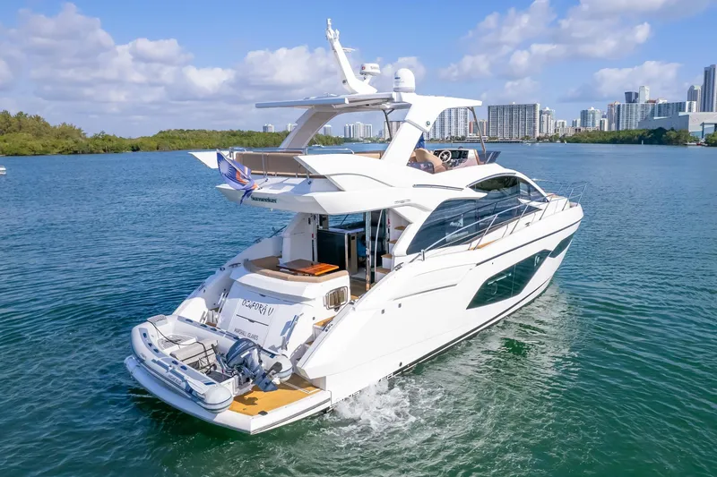 Slide: The Image of 2018 Sunseeker Manhattan 52 yacht cruising in scenic waters with city skyline backdrop. - 4