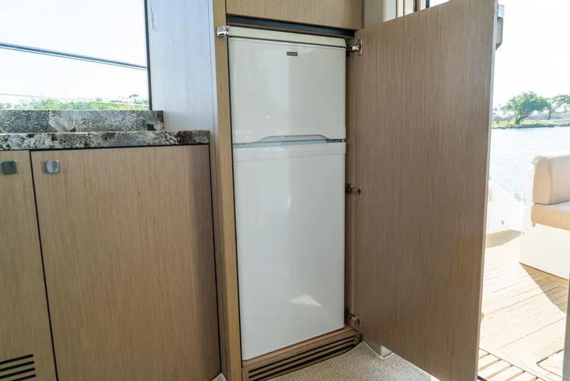 Slide: The Image of Built-in refrigerator on 2018 Sunseeker Manhattan 52 yacht, with open wooden cabinet door. - 44