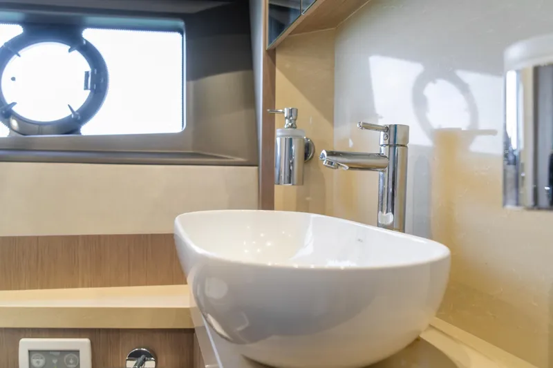 Slide: The Image of Luxurious bathroom sink on 2018 Sunseeker Manhattan 52 yacht, featuring modern fixtures and porthole window. - 65