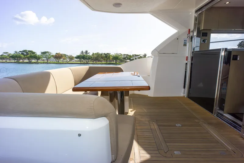 Slide: The Image of Outdoor seating area on 2018 Sunseeker Manhattan 52 yacht, featuring elegant wooden table and scenic view. - 77