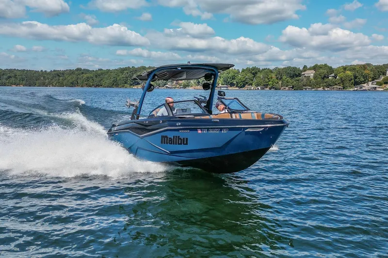 Slide: The Image of 2022 Malibu Wakesetter 25 LSV cruising on a scenic lake under a blue sky. - 1