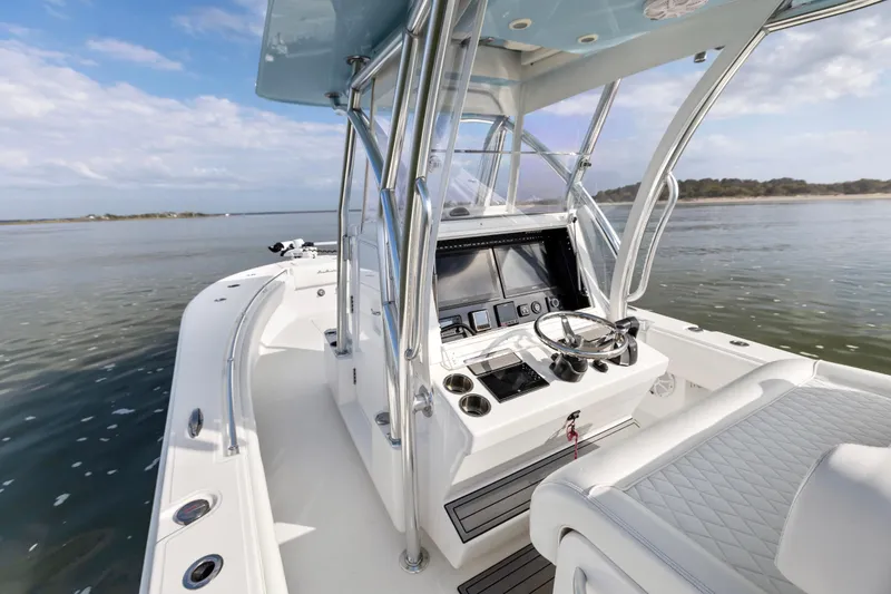 Slide: The Image of 2021 SeaHunter 28 Floridian boat interior with helm, steering wheel, and seating on calm water. - 12