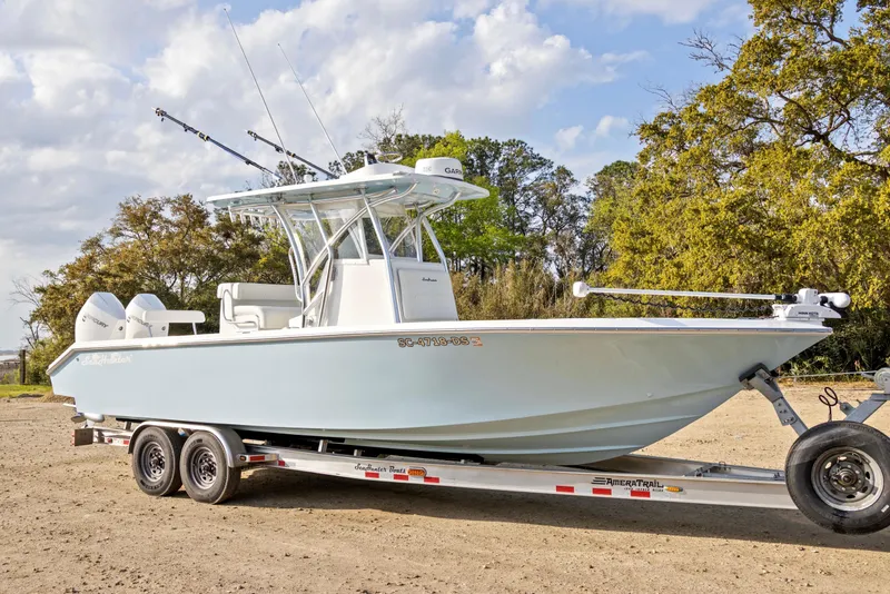 Slide: The Image of 2021 SeaHunter 28 Floridian boat on trailer, parked outdoors with trees in background. - 9