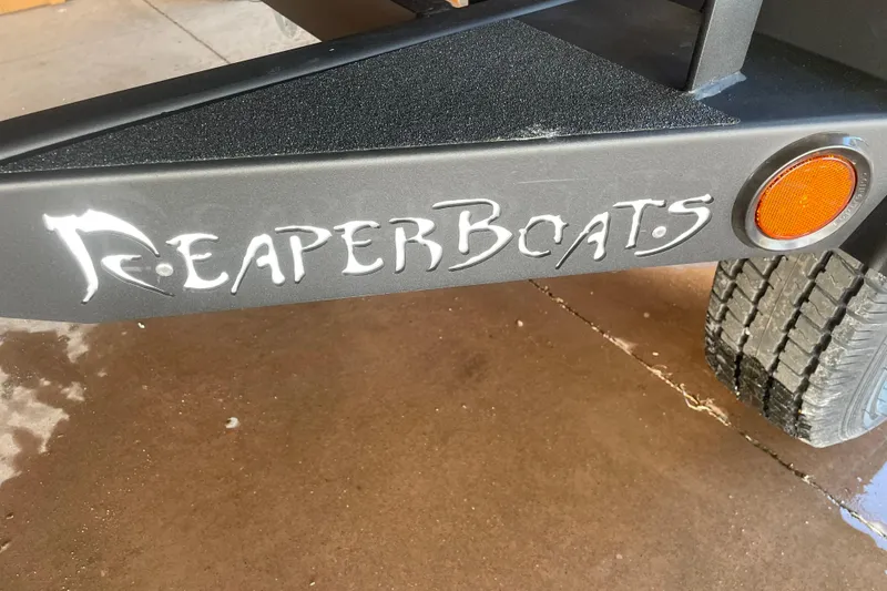 Slide: The Image of Reaper Boats logo on 2026 Reaper Boats 553 Timber Reaper trailer with tire and reflector. - 10