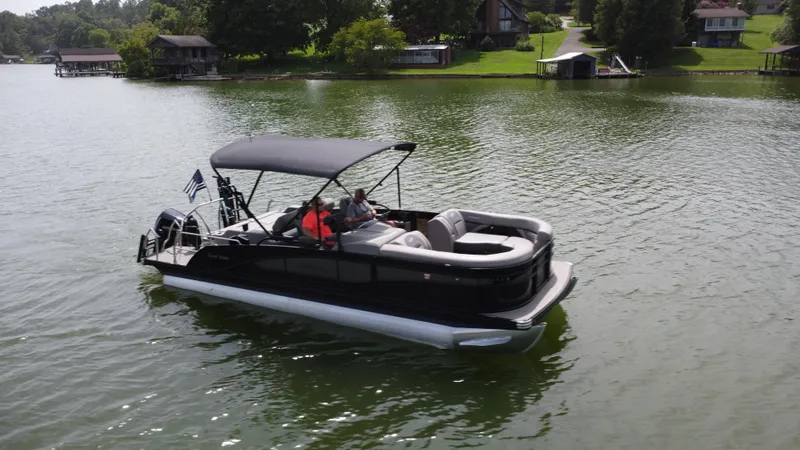 The Image of 2023 Barletta Corsa 23UC pontoon boat cruising on a serene lake. - 0