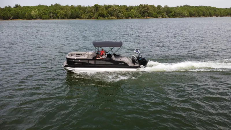 Slide: The Image of 2023 Barletta Corsa 23UC pontoon boat cruising on a lake with lush green shoreline. - 11