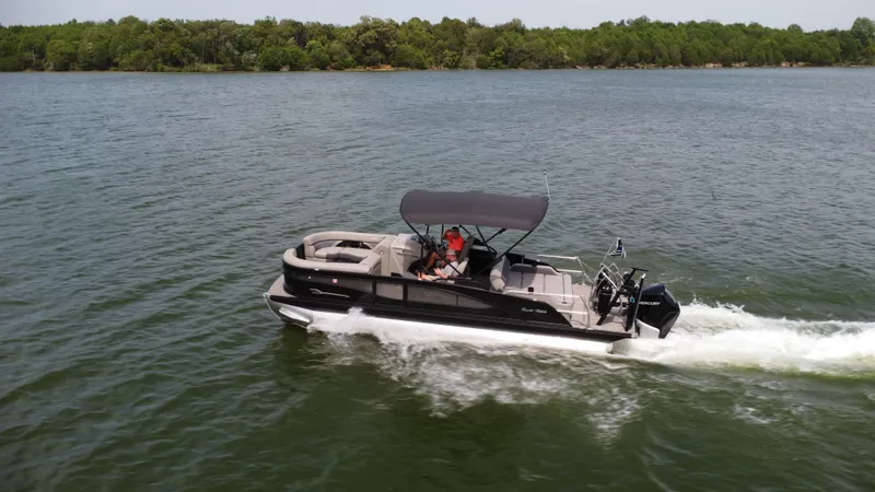 Slide: The Image of 2023 Barletta Corsa 23UC pontoon boat cruising on a lake with lush green shoreline. - 12