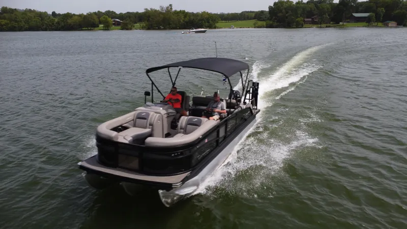 Slide: The Image of 2023 Barletta Corsa 23UC pontoon boat cruising on a lake with lush green surroundings. - 14