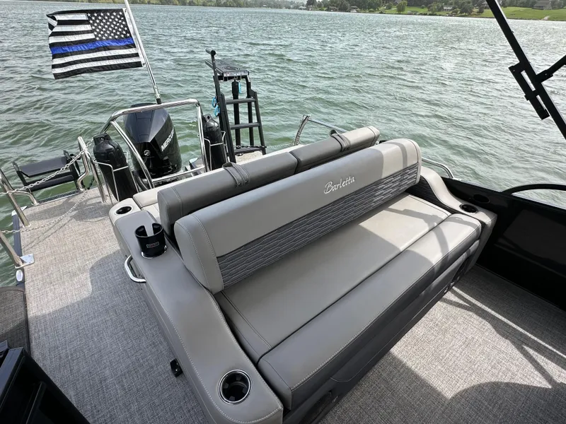 Slide: The Image of 2023 Barletta Corsa 23UC boat with seating, cup holders, and flag on a lake. - 19