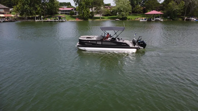 Slide: The Image of 2023 Barletta Corsa 23UC pontoon boat cruising on a serene lake. - 2